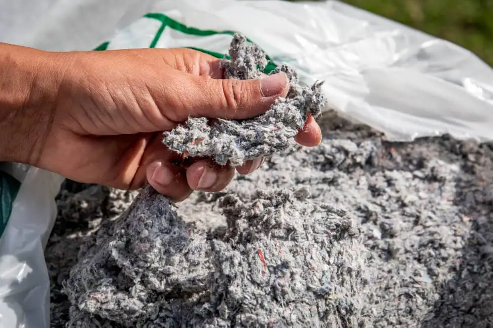 Main tenant de la ouate de cellulose, prête à être soufflée dans des combles perdus à Dijon